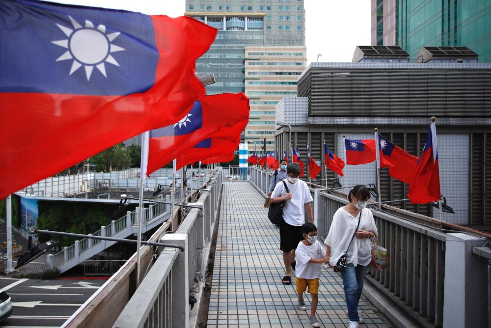 A kid and his guardian walk across a footbridge in Taipei, where Taiwan flags flutter ahead of the island’s national day, amid rising tensions with China, in Taipei, Taiwan, on October 5, 2022.