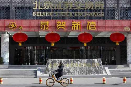A woman cycles past the Beijing Stock Exchange building adorned with Lunar New Year decorations, on the Financial Street in Beijing, China, February 8, 2024. Reuters/Florence Lo