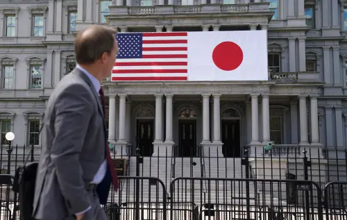 A man passes Japanese and U.S. flags hanging side by side on the Eisenhower Executive Office Building ahead of next week’s Biden-Kishida summit, April 5, 2024.