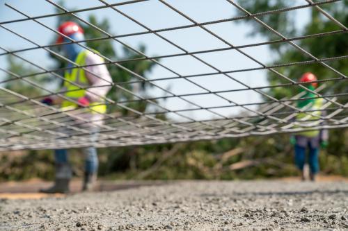 A steel wire net with construction workers in the background indicating a safety net for ABAWDs