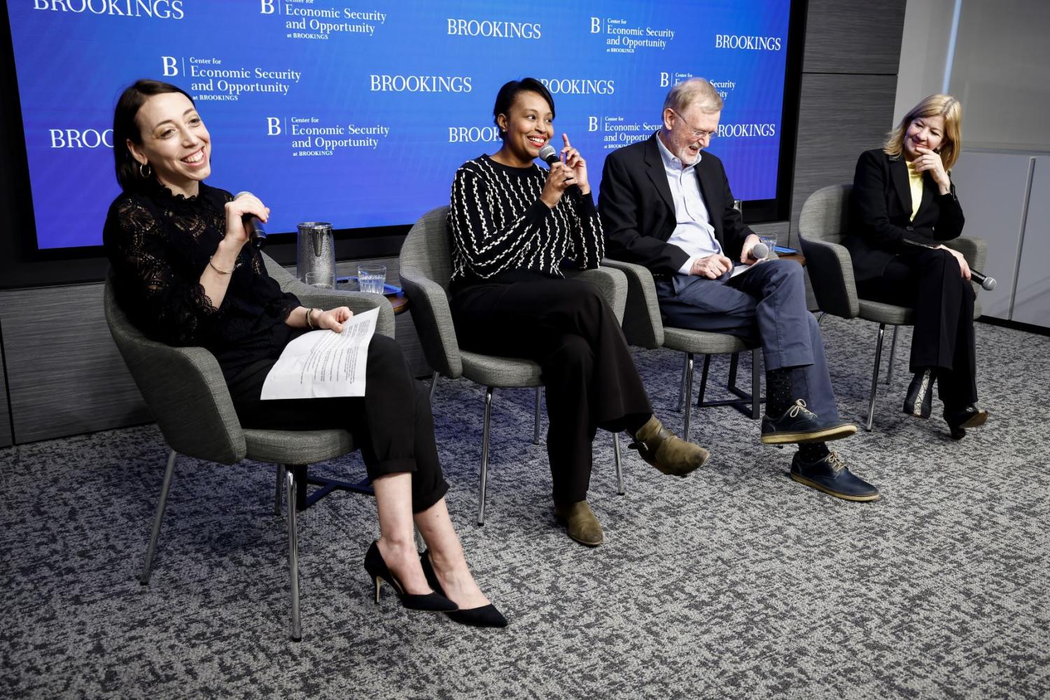 Moderator and three panelists, all seated, participating in a discussion