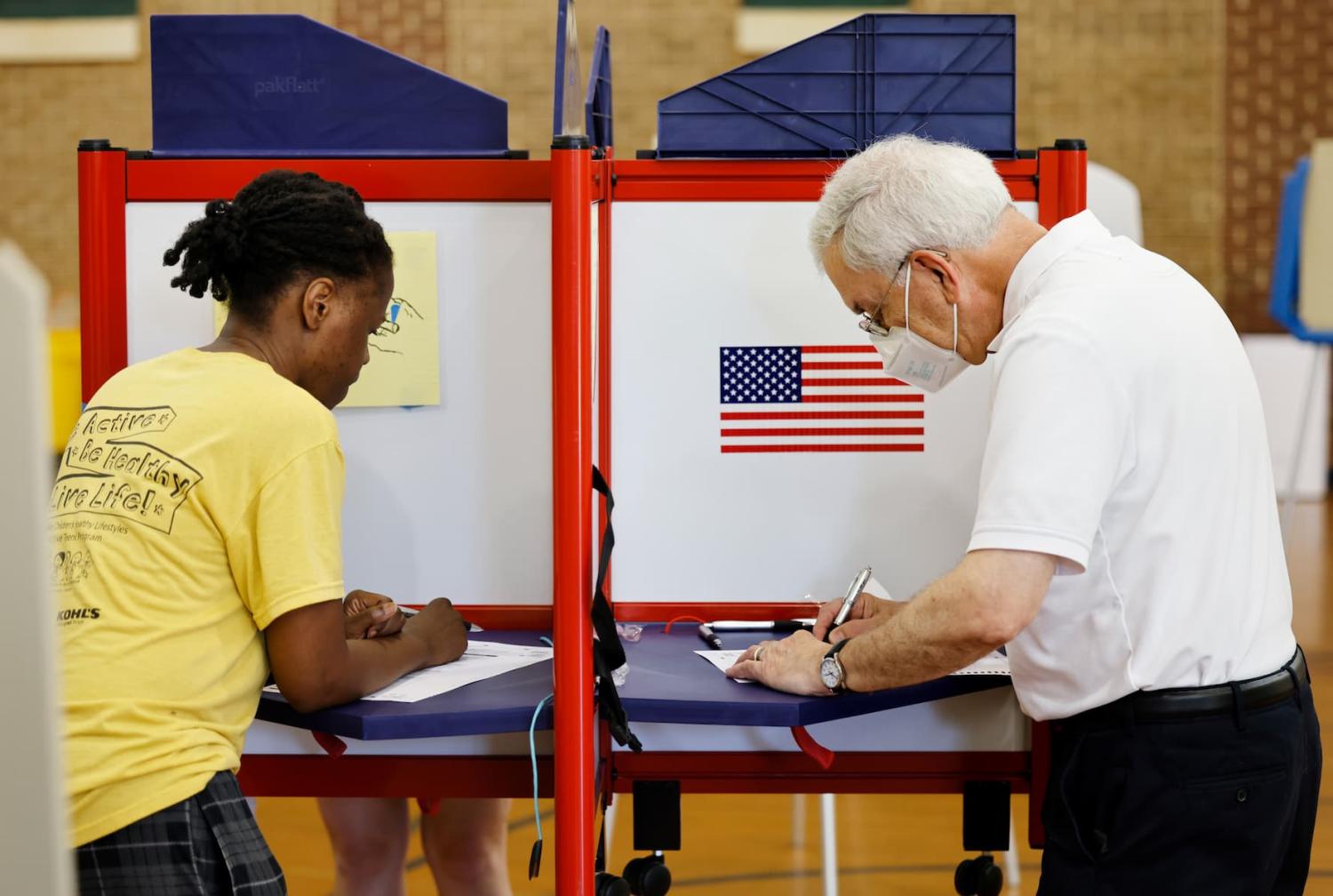 A black woman and white man mark their ballots at a voting site during primary elections in Chapel Hill, North Carolina, U.S., May 17, 2022.