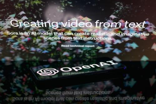 The OpenAI logo is being displayed on a smartphone with the Sora text-to-video generator visible in the background in this photo illustration, taken in Brussels, Belgium, on February 16, 2024.