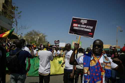 A Senegalese holds a sign that reads "No to constitutional coup d'etat" during a march to protest the postponement of the February 25 presidential election. Dakar, Senegal February 17, 2024.