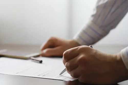 A man fills out a form. Male hand with pen makes notes in office.
