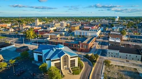 Muncie, IN with gorgeous golden glow at sunset with blue sky aerial City of Muncie building