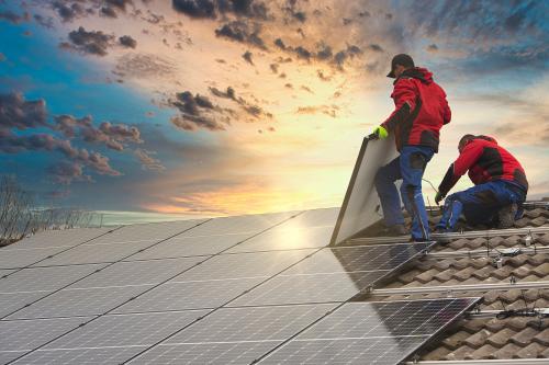 Installing solar photovoltaic panel system. Solar panel technician installing solar panels on roof. Alternative energy ecological concept.