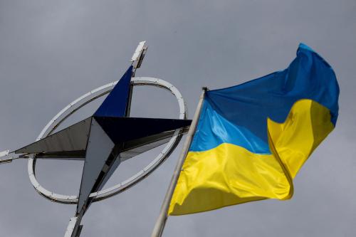 Ukrainian national flag is pictured in front of the NATO emblem