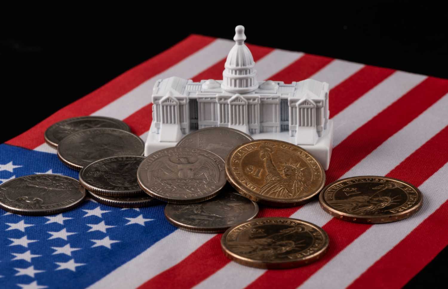 Model capitol building and pile of coins