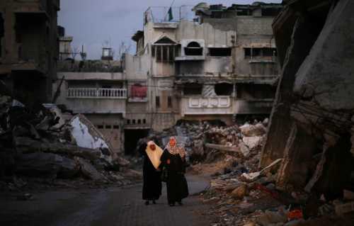 Palestinian women walk near the ruins of houses, which witnesses said were destroyed by Israeli shelling during the most recent conflict between Israel and Hamas, in the east of Gaza City December 1, 2014.