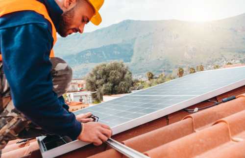 Construction worker installs solar panel on rooftop.