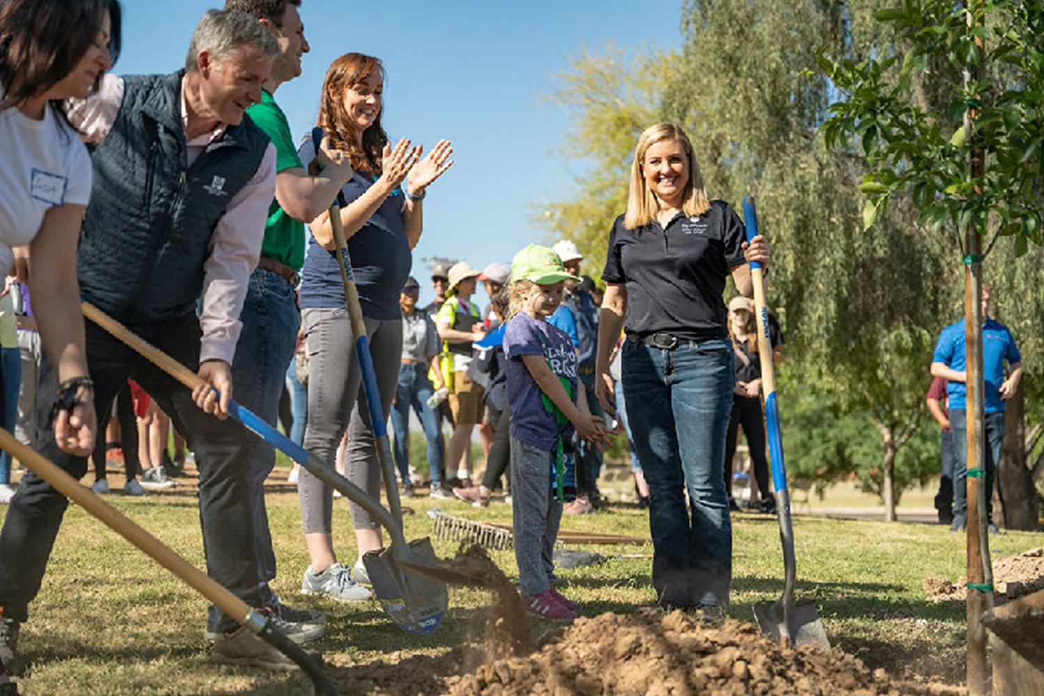 Mayor Kate Gallego participates in the planting of one of the city’s first “tree corridors”— group of people with shovels digging a hole and cheering