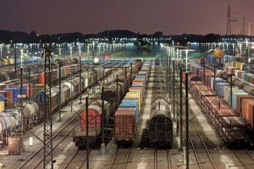 Freight trains sit stationary on tracks in a railyard at night