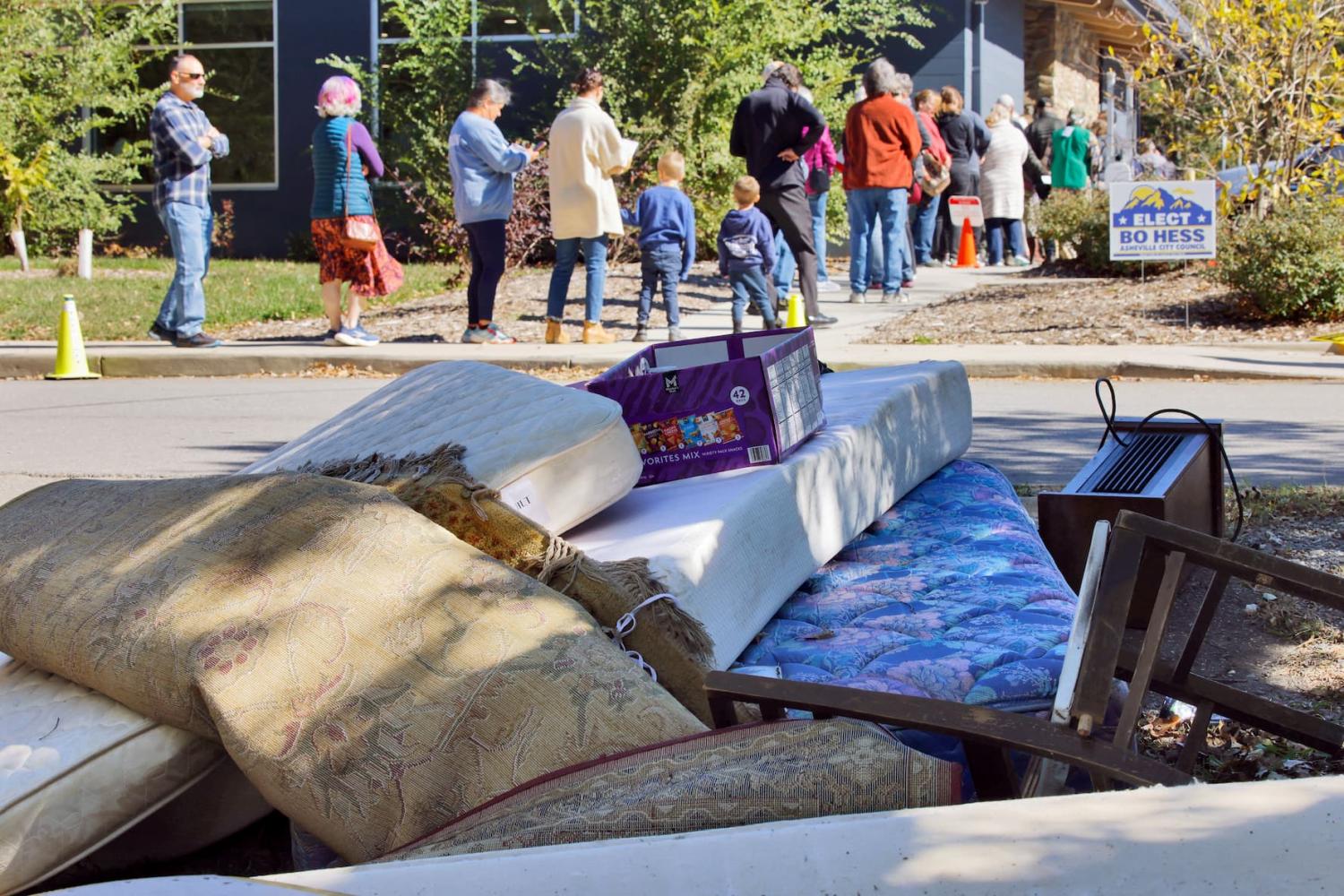 Local residents line up near a pile of Hurricane Helene debris as they wait to enter a voting site on the first day of early in-person voting in a region still severely impacted by the storm, in Asheville, North Carolina, U.S. October 17, 2024.