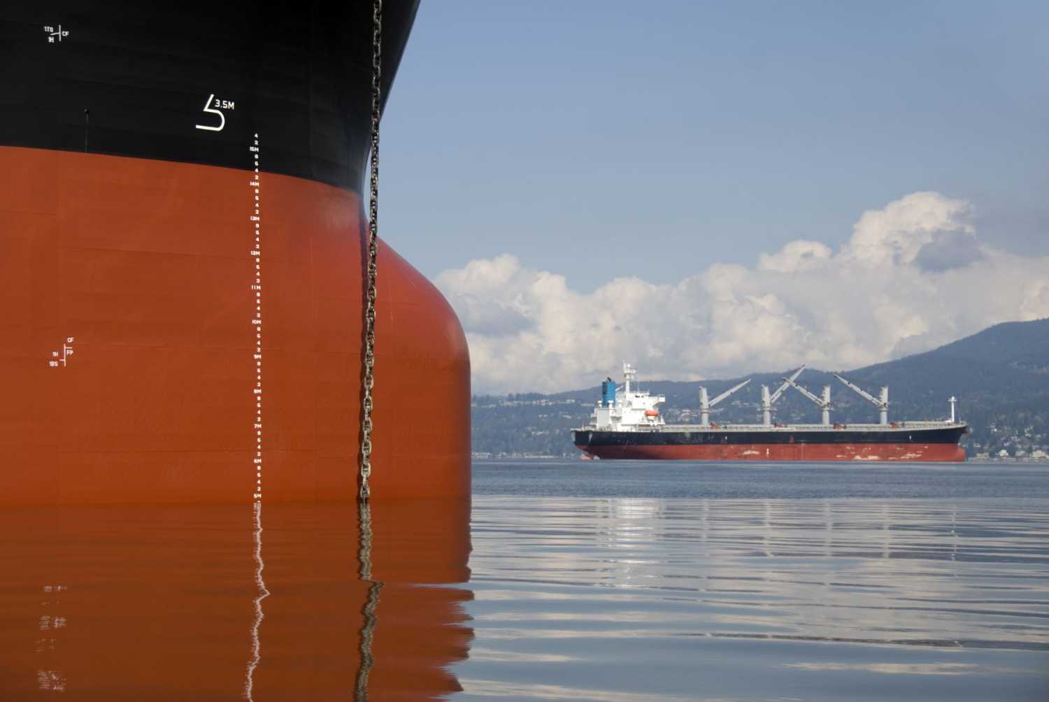Two empty freighter ships anchored in still water