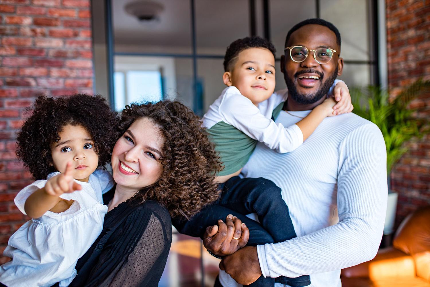 Black and Latino mixed-raced family looking at camera in cozy summer day light in living room