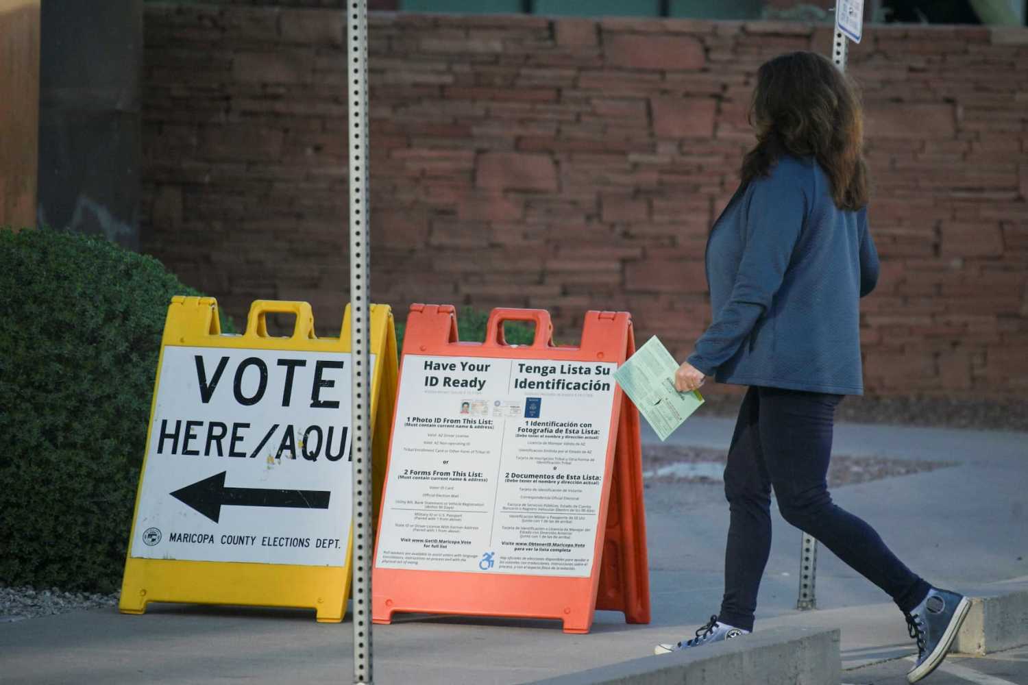 A voter carries a ballot to a polling place at the Burton Barr Central Library as the Democratic and Republican parties hold primary elections in Phoenix, Arizona, U.S. March 19, 2024.