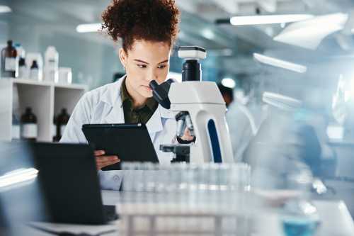 Woman, scientist and tablet with microscope in lab for experiment research, medical data or science information. Person, researcher and digital for biotechnology study