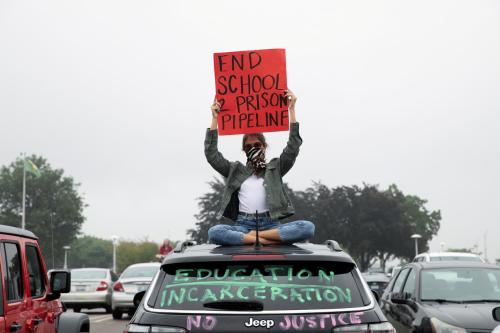 A protester sits on top of a car after a caravan protest in support of a Black Groves High School student, who was jailed due to a probation violation of not keeping up with her online schoolwork, in front of the Oakland County Circuit Court and Prosecutors Office in the Detroit suburb of Pontiac, Michigan, U.S. on July 16, 2020.