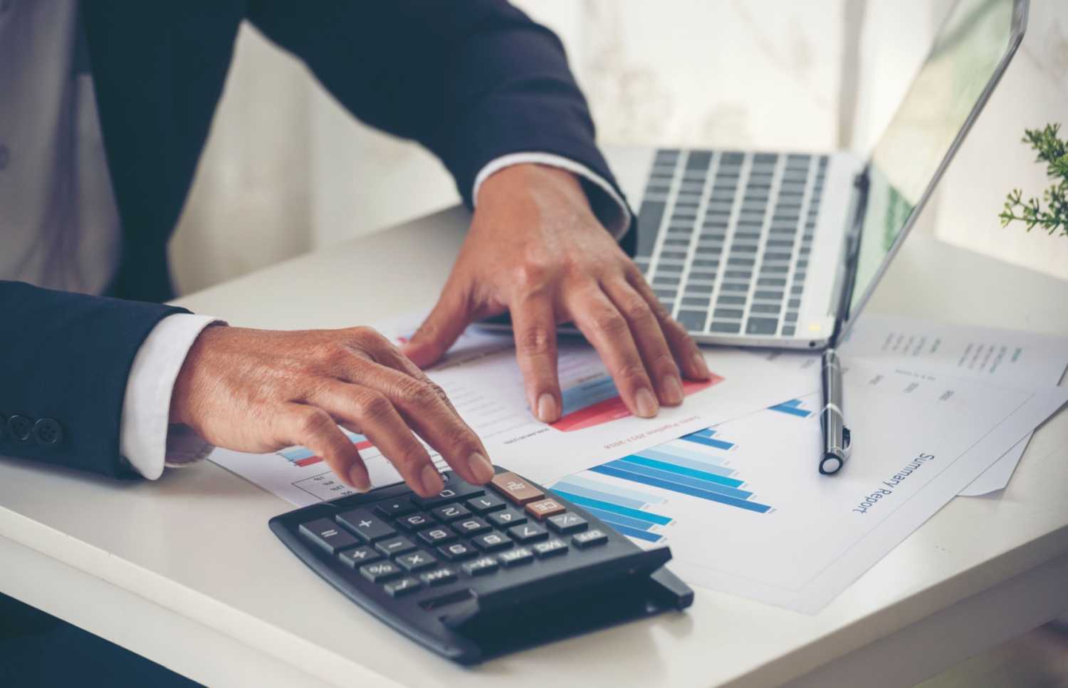 Accountant with calculator and financial graphs