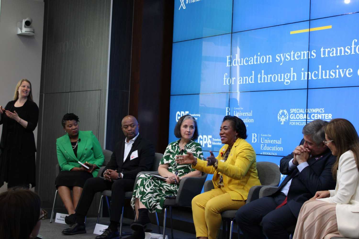 Panelists sit on stage with an ASL interpreter to the left