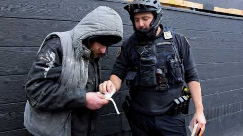 Portland police officer David Baer issues a citation to a man caught smoking fentanyl in downtown Portland, Oregon, U.S. February 7, 2024.