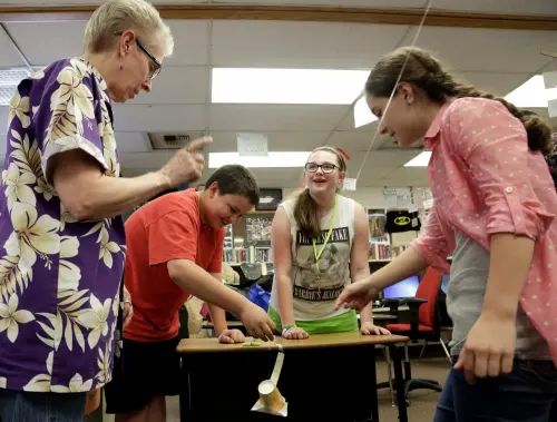 Teacher Janis Heedum helps sixth-grade students Martin Rosales, Sabrina Weber, and Karly Heitman (L-R) as they work with Boeing employees on an exercise to deliver a marble to a target using a paper cup and a zip-line during the after-school Science Technology Engineering and Math (STEM) academy held at Crestwood Elementary School in Covington, Washington May 1, 2014.