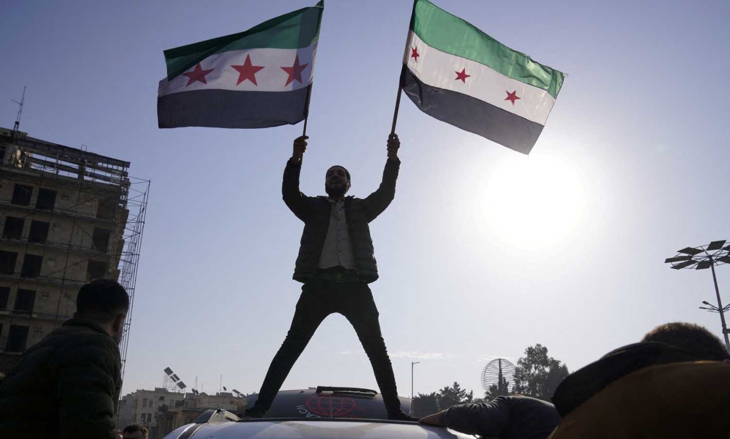A man holds Syrian opposition flags as he celebrates after Syria's army command notified officers on Sunday that President Bashar al-Assad's 24-year authoritarian rule has ended, a Syrian officer who was informed of the move told Reuters, following a rapid rebel offensive that took the world by surprise, in Aleppo, Syria December 8, 2024.