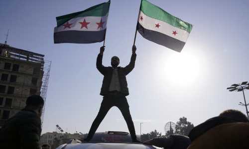 A man holds Syrian opposition flags as he celebrates after Syria's army command notified officers on Sunday that President Bashar al-Assad's 24-year authoritarian rule has ended, a Syrian officer who was informed of the move told Reuters, following a rapid rebel offensive that took the world by surprise, in Aleppo, Syria December 8, 2024.