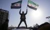 A man holds Syrian opposition flags as he celebrates after Syria's army command notified officers on Sunday that President Bashar al-Assad's 24-year authoritarian rule has ended, a Syrian officer who was informed of the move told Reuters, following a rapid rebel offensive that took the world by surprise, in Aleppo, Syria December 8, 2024.