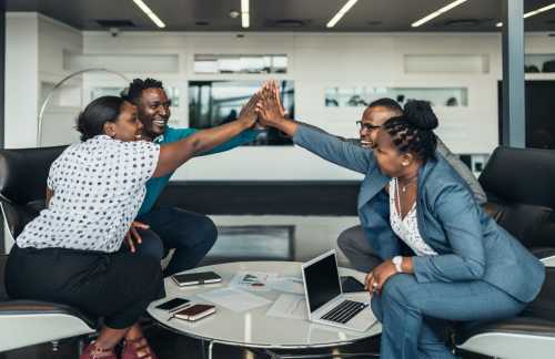 Co-workers seated around a table high-five one another