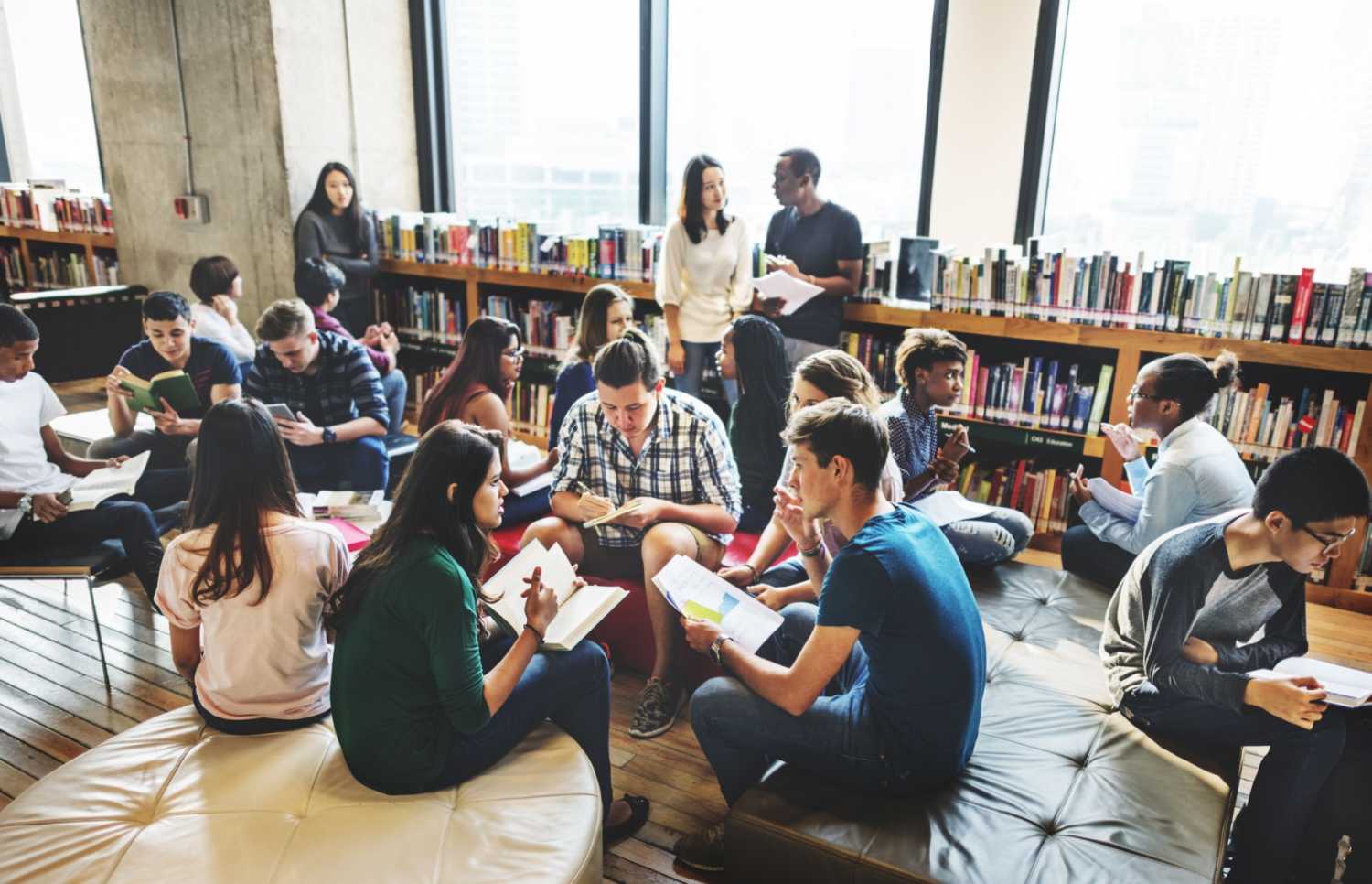 A class of college students in a library, appearing to have broken off into small groups as for a class activity