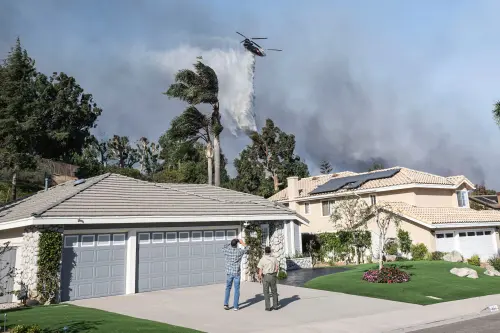 Highland Terrace residents look upon a water drop made by Coulson water tanker helicopter. The Mountain Fire blazes through Camarillo with help from the Santa Ana winds.