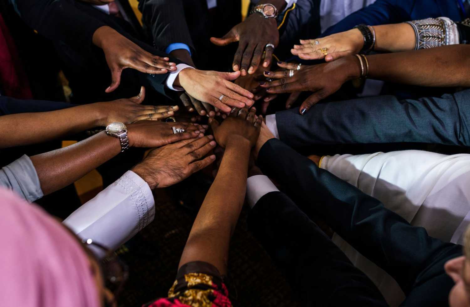 Many hands reach together, as if to kick off a project