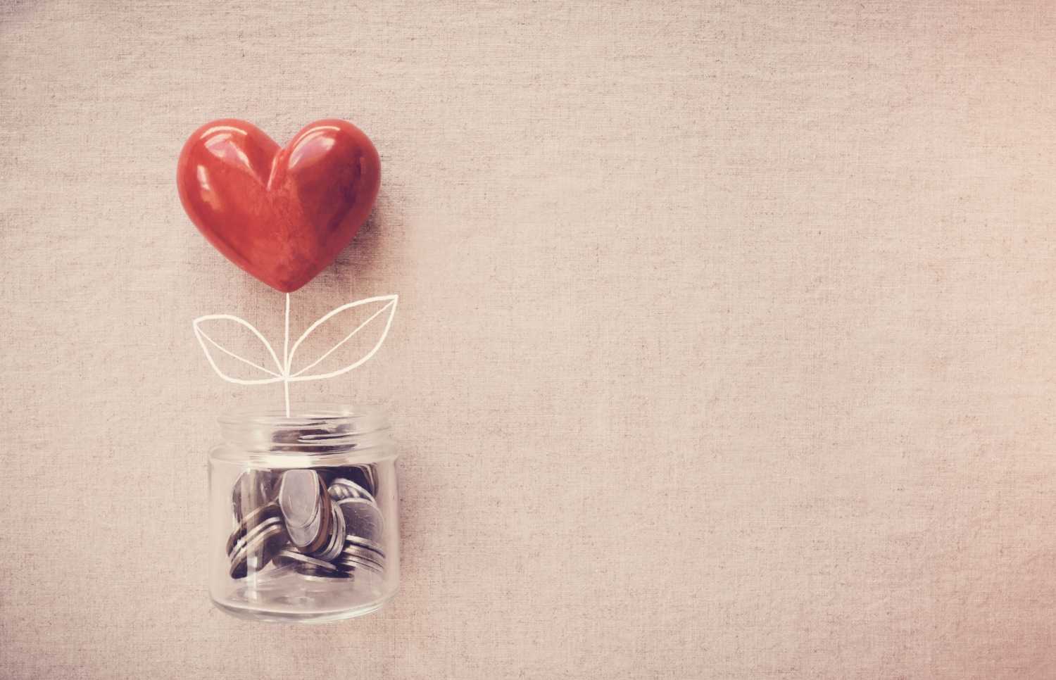 A heart styled as a flower growing out of a jar of coins.