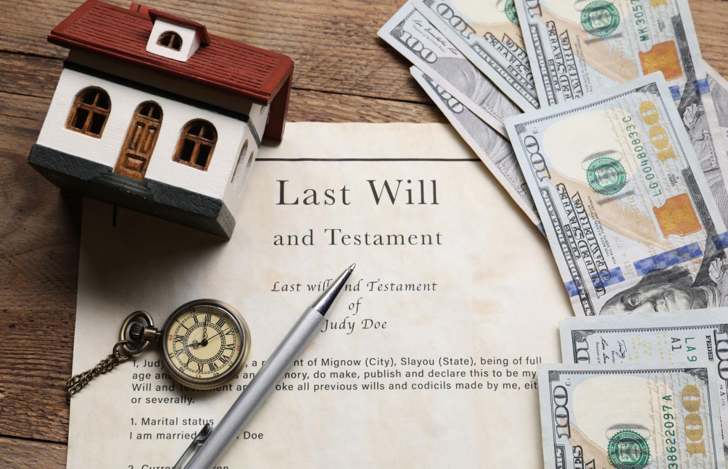 Money, model house, and pocket watch on top of a will.