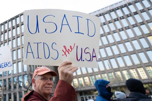 Man holds sign that reads USAID AIDS the USA outside government building