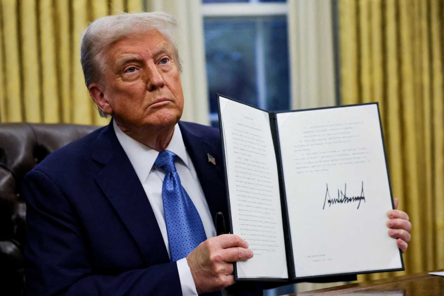 U.S. President Donald Trump holds a signed executive order in the Oval Office at the White House in Washington, U.S., January 31, 2025.