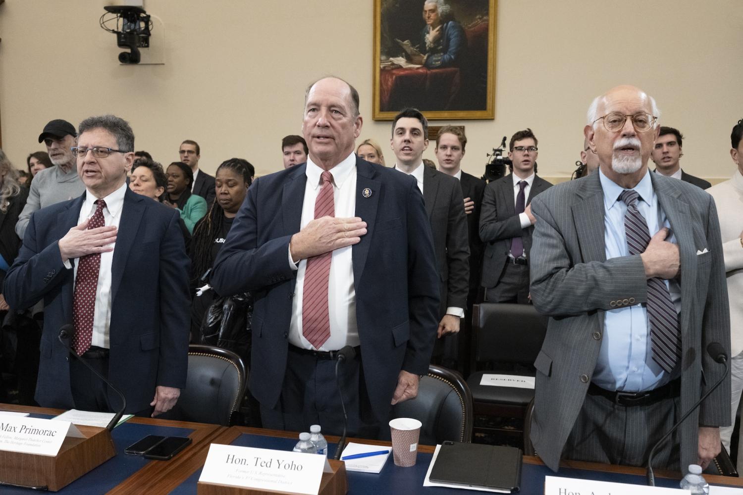 Image showing Max Primorac, former USAID official; former Rep. Ted Yoho (R-FL); and Andrew Natsios, former USAID administrator, recite the Pledge of Allegiance at a House Foreign Affairs Committee hearing, “The USAID Betrayal,” on Capitol Hill, Feb. 13, 2025.