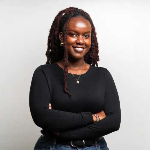 Headshot of Grace Chege. She is wearing a black shirt and a silver necklace. She is smiling.