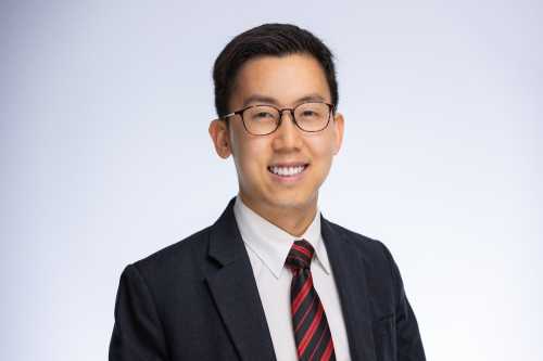 Headshot of Shaun Ee. He is wearing glasses and a suit with a striped tie.