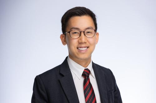 Headshot of Shaun Ee. He is wearing glasses and a suit with a striped tie.