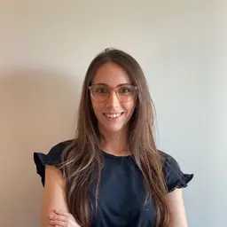 Headshot of Maia Levy-Daniel. She is in a navy blue blouse and wears glasses.