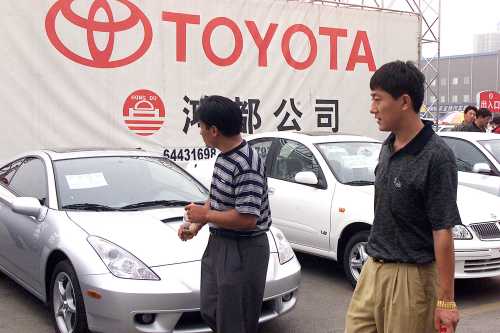 Chinese car shoppers pass by Japanese import cars at a car lot in Beijing July 3, 2001.