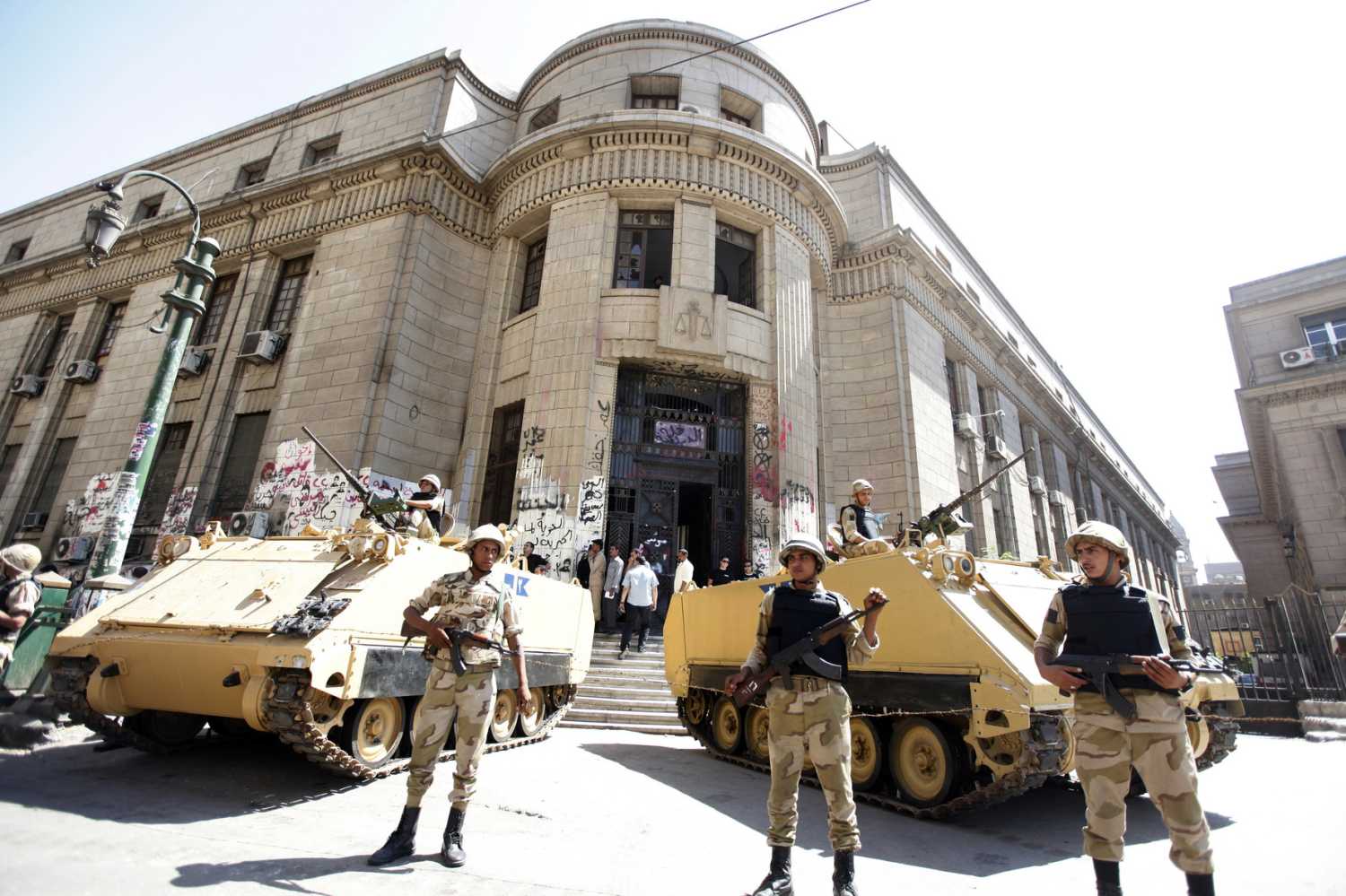 Egyptian army personnel stand guard as protesters and activists shout slogans in protest against former president Hosni Mubarak's release from prison, in front of the courthouse and the Attorney General's office in downtown Cairo August 23, 2013.