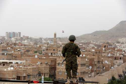 An army soldier loyal to the Houthi movement stands guard on the roof of a building overlooking the site of a demonstration against Saudi-led airstrikes in Sanaa, Yemen, July 18, 2016.