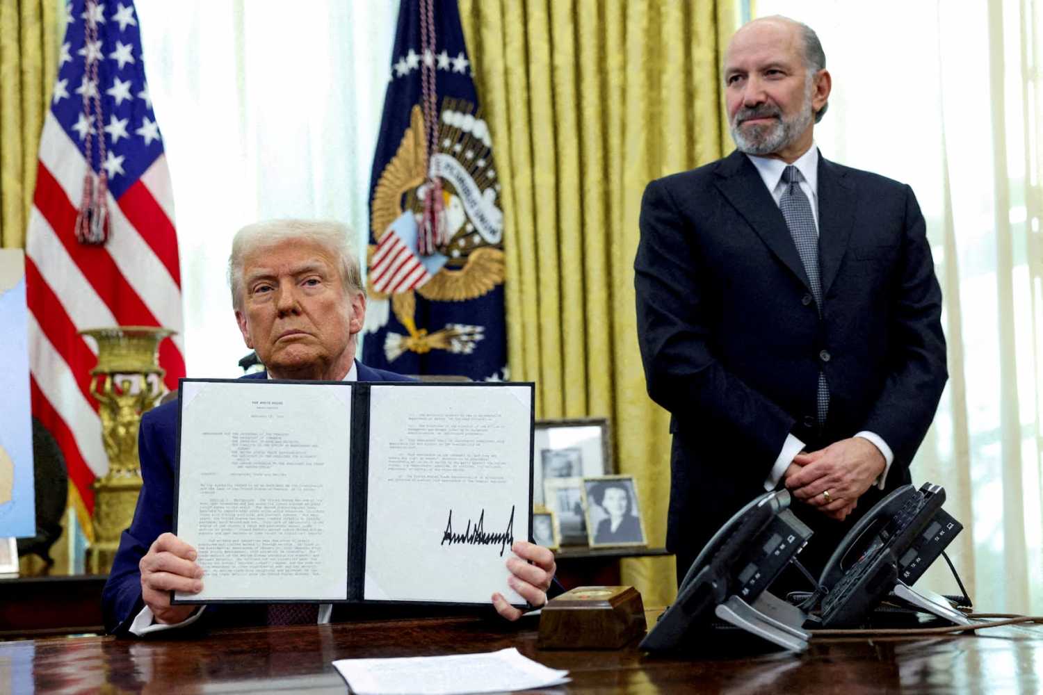 U.S. President Donald Trump holds an executive order about tariffs increase, flanked by U.S. Commerce Secretary Howard Lutnick, in the Oval Office of the White House in Washington, D.C., U.S., on February 13, 2025. REUTERS/File Photo