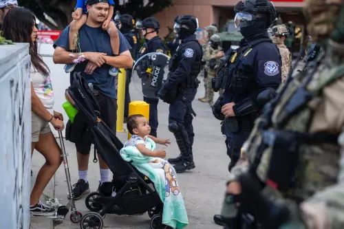 A family stand as law enforcement stand guard outside the Federal Building during a protest