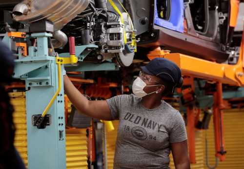 A woman works on a vehicle assembly line