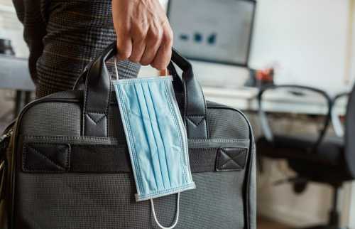 Man with surgical mask and briefcase in his hand.